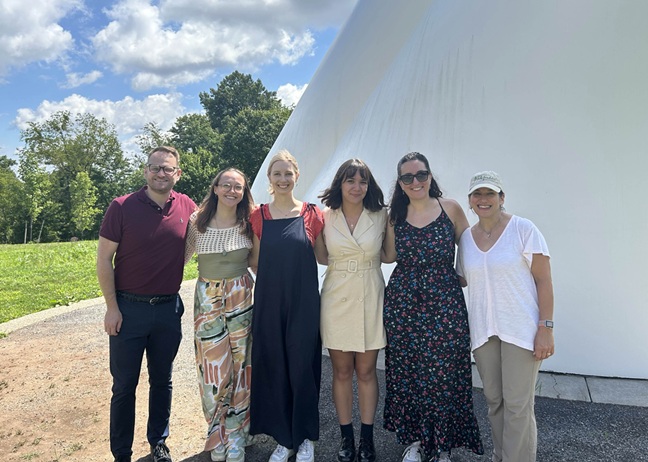 A group of six people pose for a group photo in the Carol R. Brown Sculpture Garden at Hartwood Acres Park