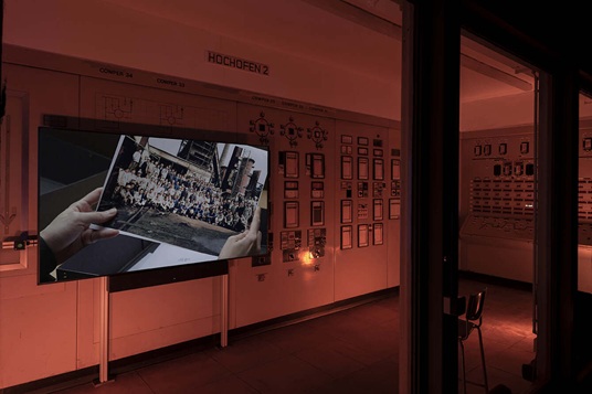 Art installation that features photographs hanging in a dimly lit room