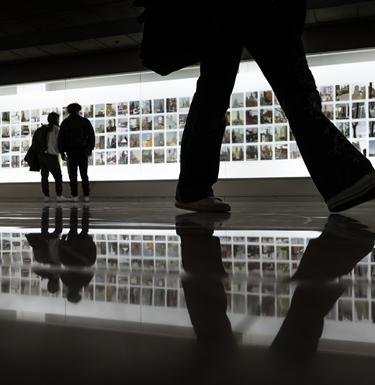 People looking at a lit up picture wall art installation