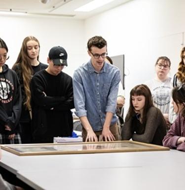 A professor discusses a piece of artwork with students around a table