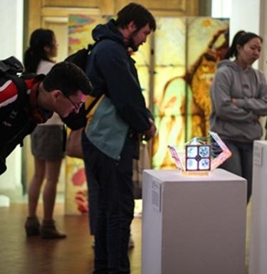Student studies artwork displayed on a pedestal 