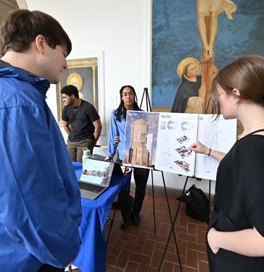 Student explains a research poster to another student attending the HAAARCH Expo