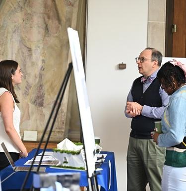Student converses with attendees about their display at an educational fair