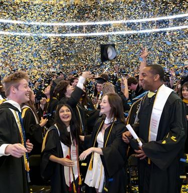 Students celebrate the end of the graduation ceremony as confetti falls