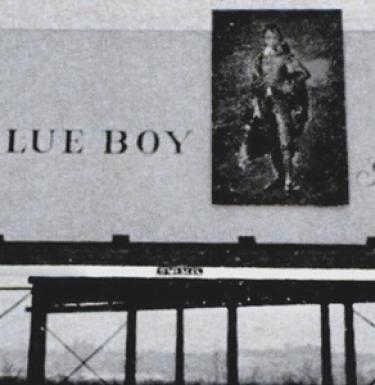 Black and white picture of a billboard that reads "The Blue Boy"